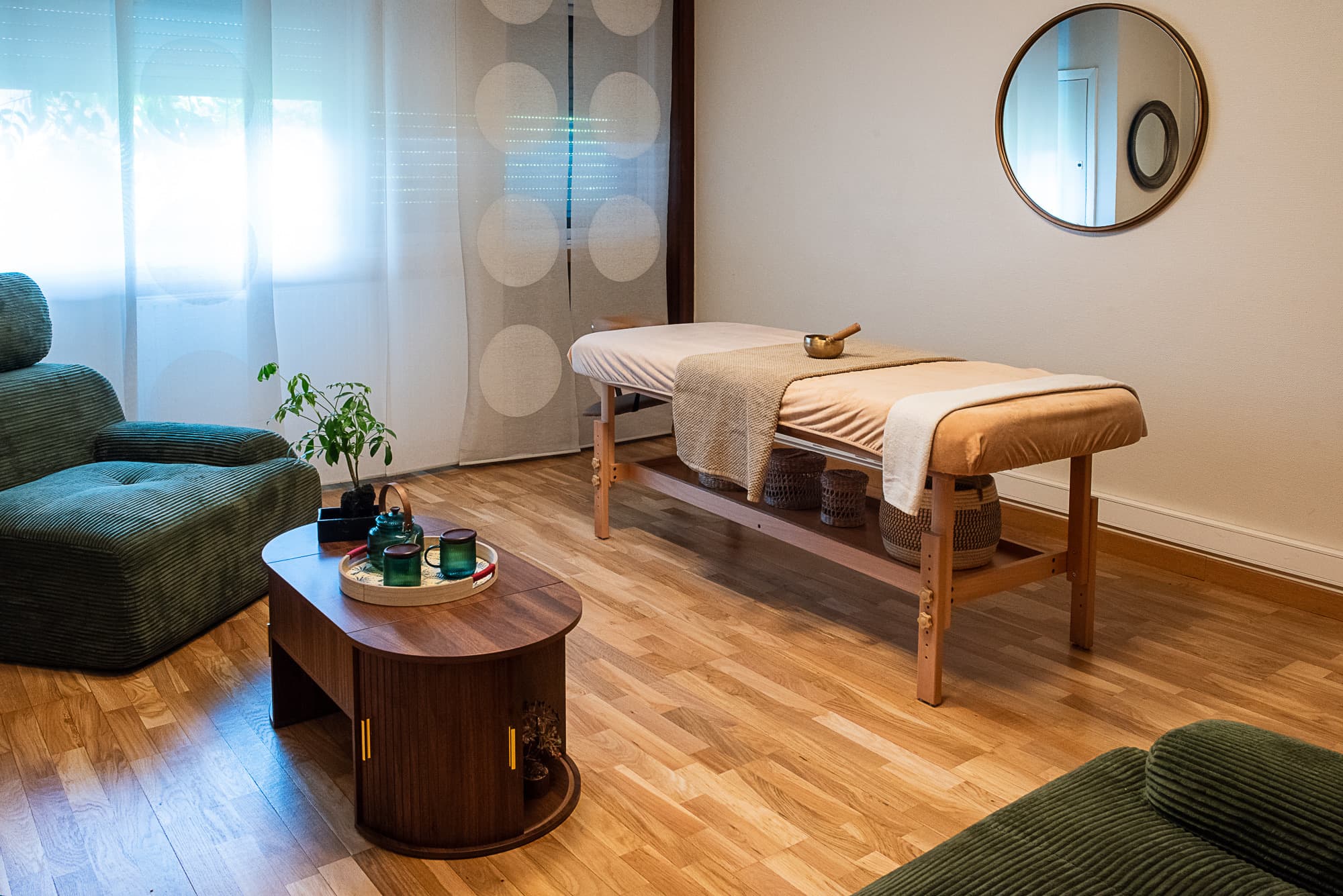 La salle de massage YUJA à Rennes : table de massage, fauteuils en velours vert et tisanerie