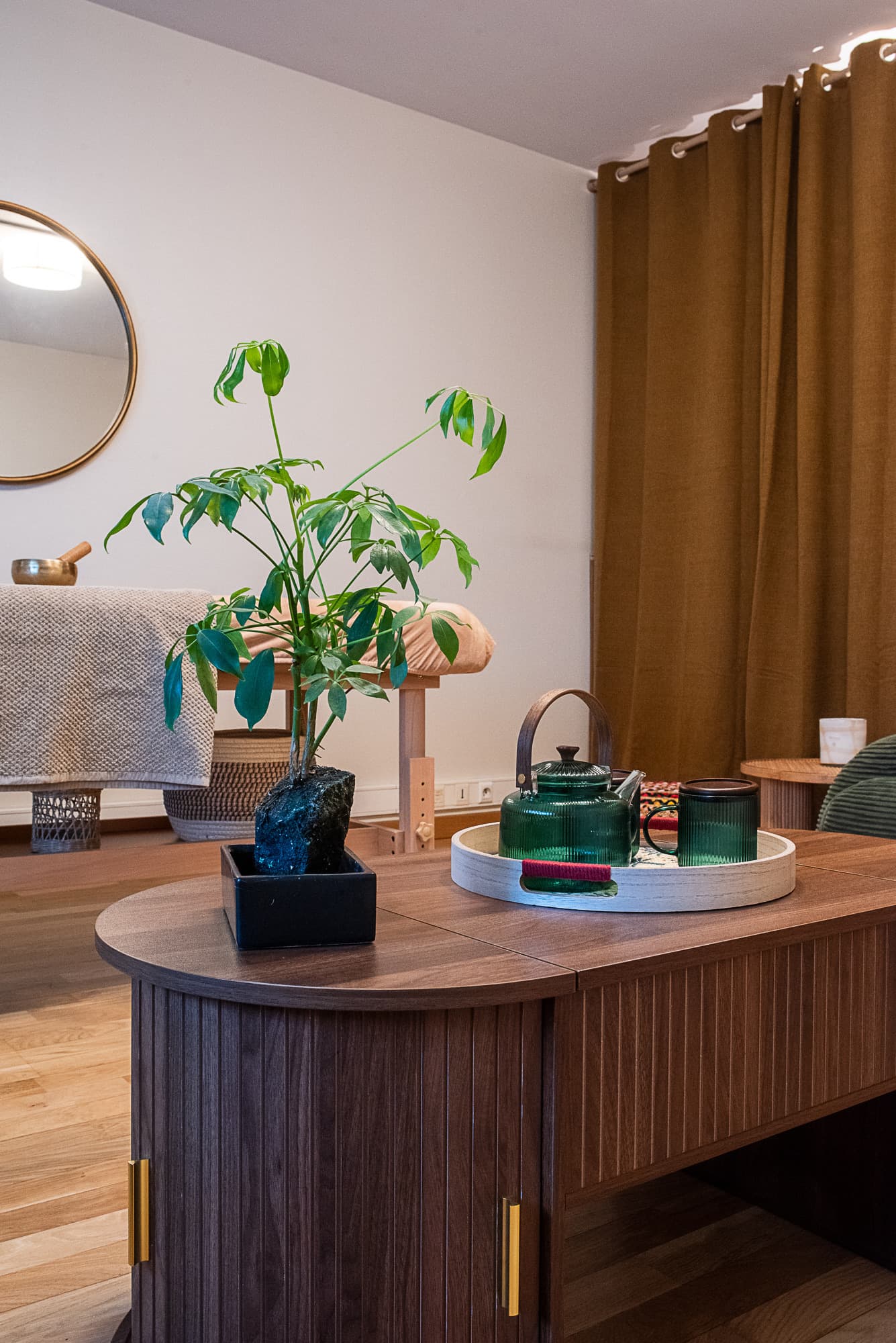Détail du salon d'accueil : plante, plateau de thé et rideaux camel